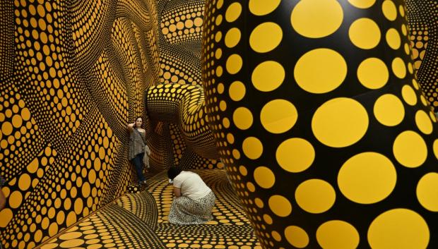 Unos visitantes toman fotografías mientras recorren la instalación 'Infinity Mirrored Room'