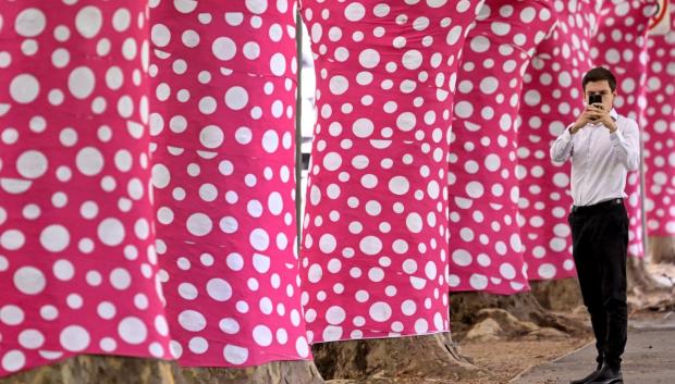 Un hombre fotografía algunos de los 60 plátanos envueltos en un diseño de lunares rosas y blancos creados por la artista contemporánea japonesa Yayoi Kusama