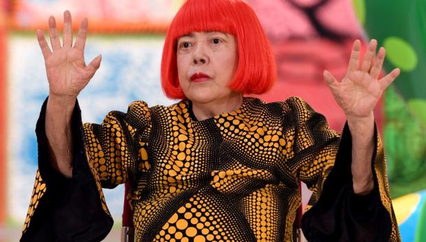 La artista japonesa Yayoi Kusama saluda durante una sesión fotográfica