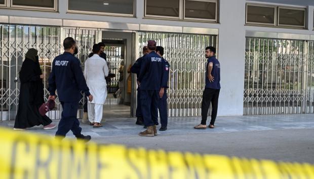 Unos pacientes llegan mientras personal de seguridad privada permanece en el exterior de la unidad de salud materno-infantil del hospital del Instituto de Ciencias Médicas de Pakistán (PIMS)