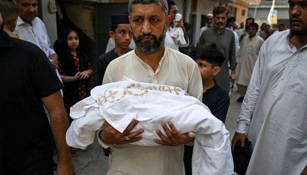 Un hombre lleva en brazos el cuerpo de un recién nacido fallecido tras un incendio en la unidad de salud materno-infantil del hospital del Instituto de Ciencias Médicas de Pakistán (PIMS)