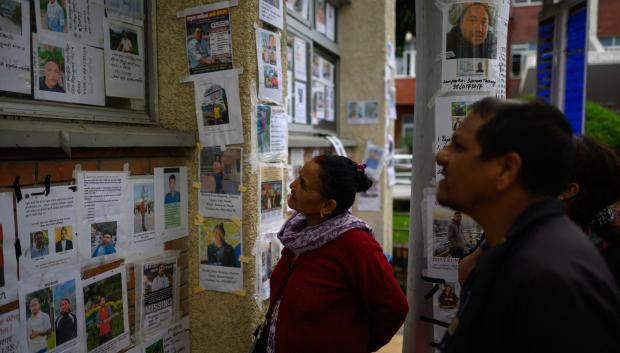 Familiares observan fotografías de personas desaparecidas tras las inundaciones