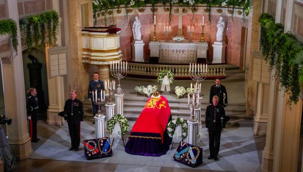 Se muestra el féretro del rey Harald V de Noruega, con las insignias reales —la corona del rey y la espada del reino— depositadas sobre él, durante la capilla ardiente instalada en la capilla del Palacio Real de Oslo