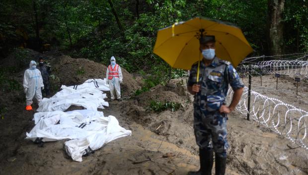 Personal de seguridad permanece junto a los cuerpos no identificados de víctimas de las inundaciones