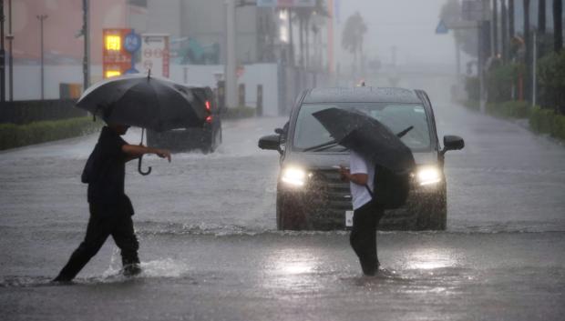 Personas cruzan una calle inundada en Funabashi, prefectura de Chiba, cerca de Tokio