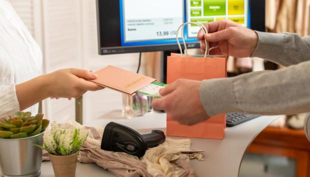 Pasajera mostrando su tarjeta de embarque para pagar en un aeropuerto