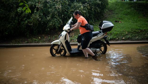 Una mujer arrastra su moto a través de la lluvia acumulada en Cataluña