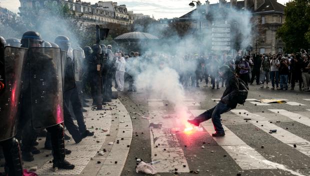 Una persona patea una bengala contra los agentes de policía que dispersan a los manifestantes al final de una protesta que forma parte de una jornada nacional de movilizaciones convocada por estudiantes de secundaria