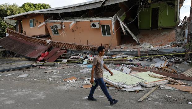 Un hombre camina cerca de una vivienda afectada el terremoto en Tonosí