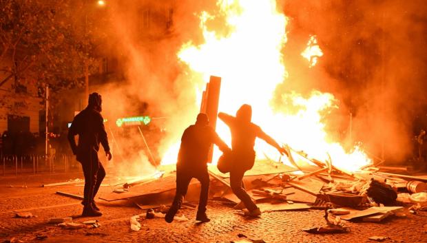 Varios manifestantes alimentan una hoguera con distintos materiales en el bulevar Haussmann de París