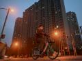 Un hombre monta en bicicleta frente a un complejo de viviendas de Evergrande en China