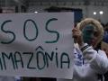 Una mujer muestra un cartel en el que pide ayuda para salvar la Amazonia brasileña