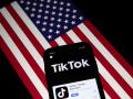 Fotografía de archivo que muestra la aplicación TikTok en la pantalla de un teléfono con la bandera estadounidense de fondo