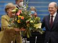 El nuevo canciller Olaf Scholz entrega un ramo de flores a Angela Merkel en su última reunión con el gabinete
