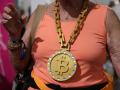 A woman wears a medallion with the bitcoin symbol at a cryptocurrency conference.