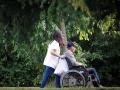 Una mujer pasea con un hombre en silla de ruedas junto a una residencia en San Sebastián