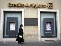 Una monja camina por delante de la sede del banco Credito Artigiano