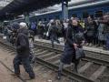 Las personas cruzan las vías del tren mientras intentan llegar a un tren de evacuación en la estación principal de trenes de Kiev