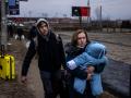 Una mujer carga a su hijo mientras huyen de la ciudad de Irpin, al noroeste de Kiev