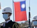Dos guardias de honor taiwaneses desfilan durante una ceremonia militar con la bandera estatal de fondo