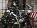Varios bomberos retiran el cuerpo de una mujer de un edificio de viviendas bombardeado, este martes
