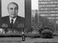 Una mujer pasa junto a un enorme retrato del líder del Partido Comunista, Leonid Brezhnev, que empequeñece el símbolo de los próximos XXII Juegos Olímpicos de Verano, justo detrás, en Moscú