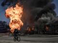 Un ciclista pedalea cerca de las llamas, vestigios de una explosión, en la ciudad ucraniana de Járkov