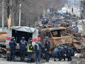 Los ingenieros ucranianos realizan la limpieza de minas entre los vehículos destruidos en una calle de Bucha