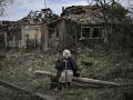Una anciana se sienta frente a las casas destruidas después de un ataque con misiles en la ciudad de Druzhkivka