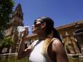 Una joven bebe agua para refrescarse en el Patio de los Naranjos de Córdoba