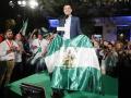 El presidente de la Junta de Andalucía, Juanma Moreno, posa con la bandera de la comunidad en la celebración de su victoria electoral