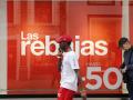Un hombre pasa junto a un comercio de Madrid, que anuncia este jueves el comienzo de las rebajas de verano