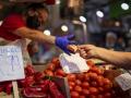 Un consumidor paga en un puesto de hortalizas del Mercado de Maravillas de Madrid