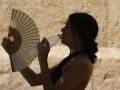 Una mujer bebe agua y se abanica mientras pasea por el barrio de la Judería de Córdoba