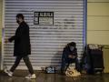 Un viandante pasa frente a una persona sin hogar en una calle de Barcelona