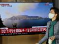 A woman walks past a television screen showing a news broadcast with live footage of the island of Ulleungdo at a railway station in Seoul on November 2, 2022. - South Korea on November 2 told residents on the island of Ulleungdo off its east coast to evacuate to bunkers after North Korea fired three short range ballistic missiles. (Photo by JUNG YEON-JE / AFP)