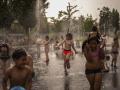 Un grupo de niños se divierte jugando con la fuente de un parque en Madrid