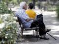 Un pensionista descansa en un banco en un parque de Madrid