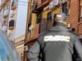 Un agente de la Policía Nacional mira en dirección a la vivienda que ha sufrido el incendio en Huelva