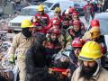 Miembros de un equipo de rescate transportan a una superviviente del terremoto