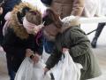 Dos niñas ucranianas refugiadas reciben bolsas con regalos en la Plaza San Amaro, en diciembre de 2022