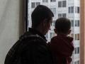 Un padre mirando por la ventana con su hijo en brazos