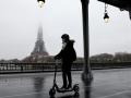 Una usuaria pasa cerca de la Torre Eiffel con su patinete