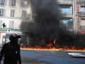 Un agente de Policía junto a una estación de bicicletas públicas ardiendo en París