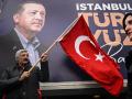Un simpatizante sostiene una bandera nacional turca delante de un cartel del presidente turco y líder del Partido de la Justicia y el Desarrollo (AK), Recep Tayyip Erdogan