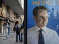 Varios jóvenes griegos caminan junto a un cartel de la campaña de el primer ministro griego y candidato oficialista Kyriakos Mitsotakis