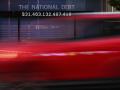 Un coche pasa frente a una parada de autobús que muestra la deuda nacional en Washington, DC