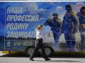 A woman walks past a contract army service mobile recruitment point in Moscow on June 14, 2023. The slogan reads "Our profession is to defend fatherland". (Photo by Natalia KOLESNIKOVA / AFP)