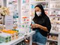 Una mujer con mascarilla mira un producto en una farmacia