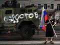 Un hombre sostiene la bandera nacional rusa frente a un vehículo militar del grupo Wagner con el cartel que dice Rostov